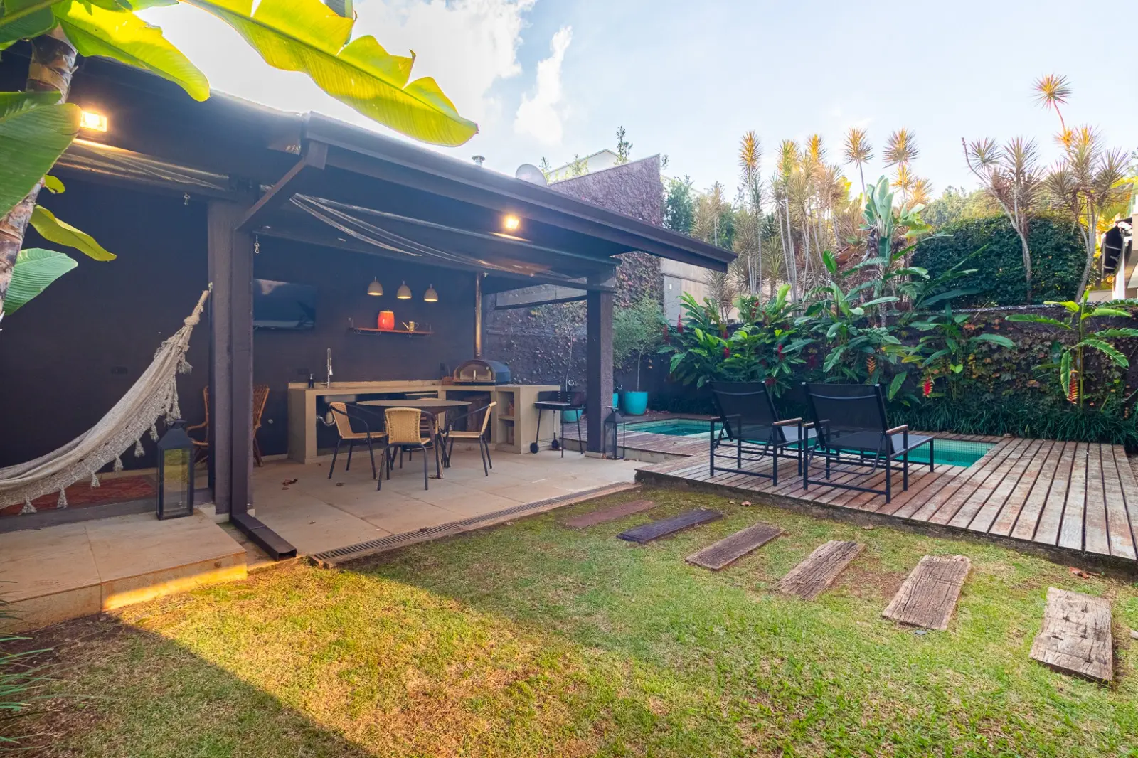 Espaço gourmet coberto com forno de pizza e jardim