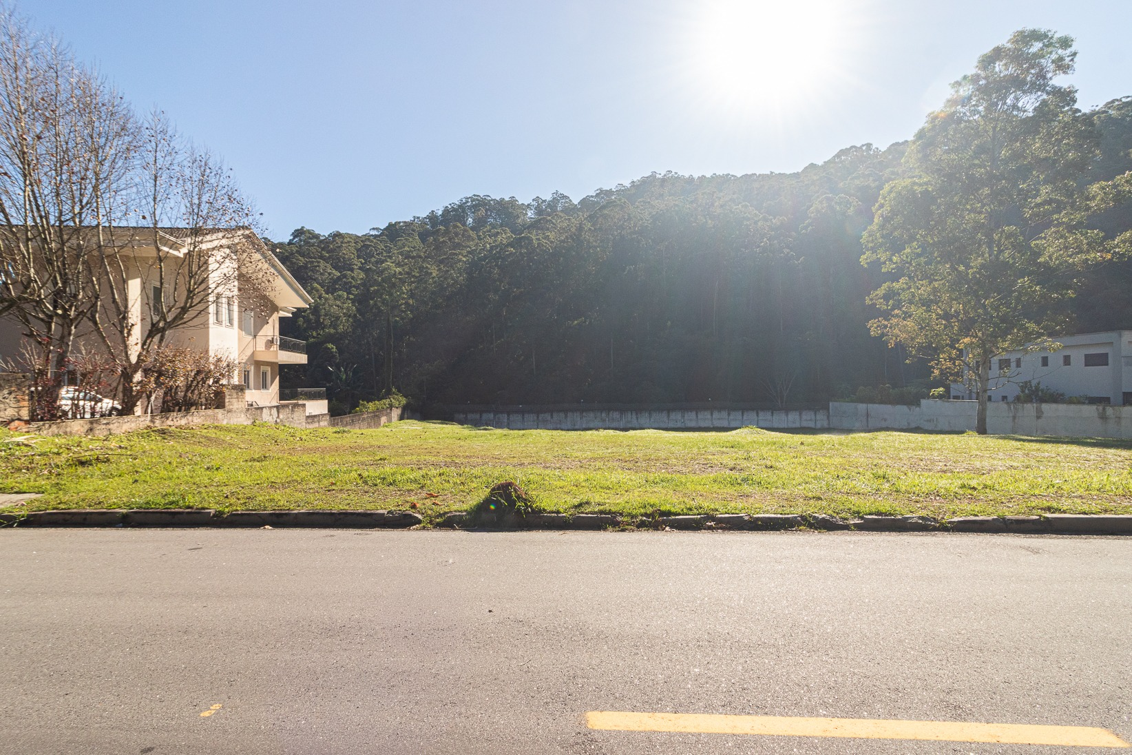 Terreno visto a partir da rua, com área verde ao fundo