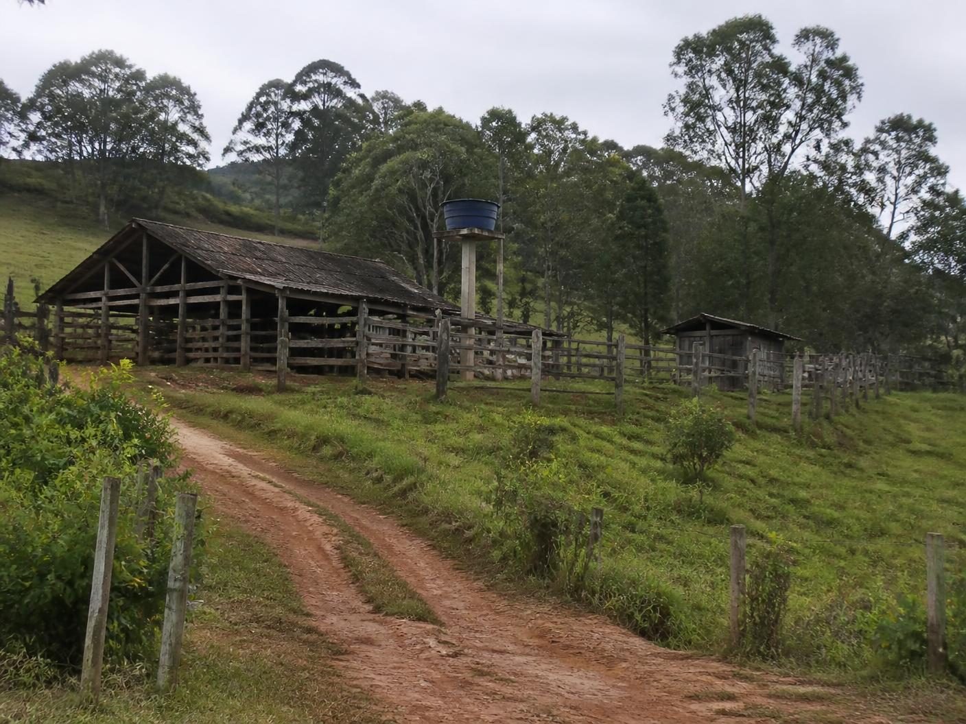 Infraestrutura rural simples com galpão, curral e estrada de acesso